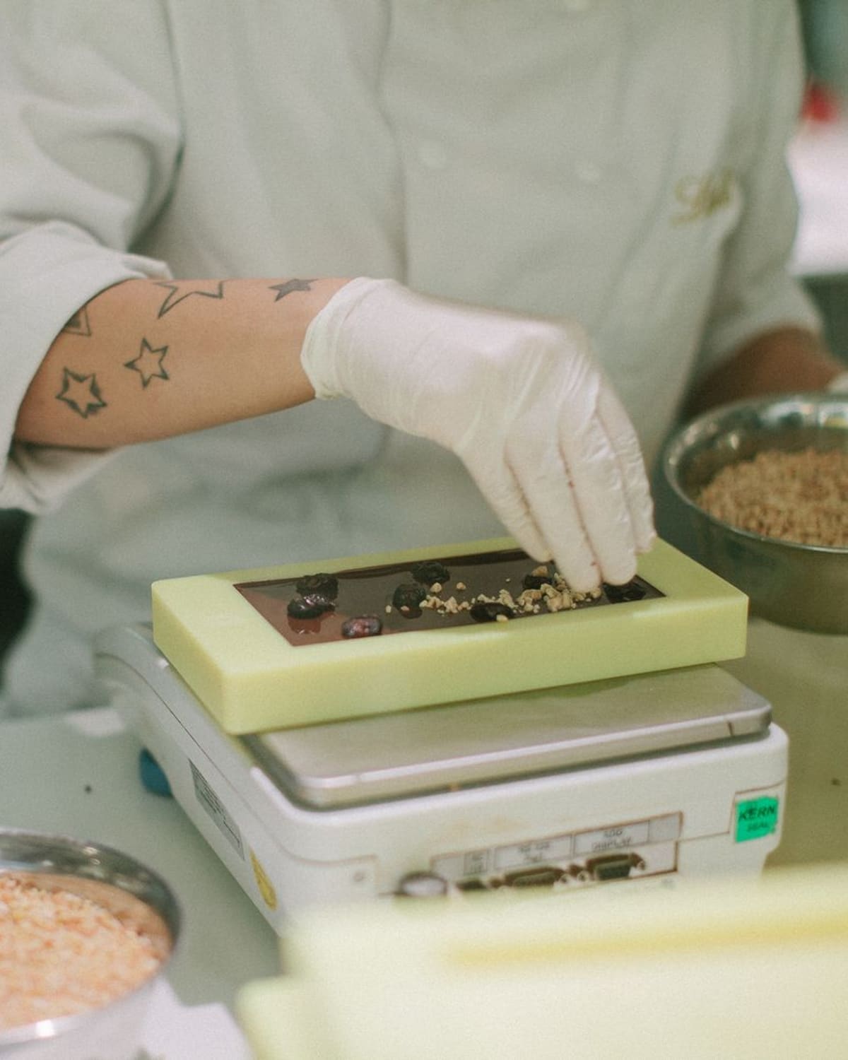 A chocolatier's gloved hand finishing a bar of chocolate in the kitchen