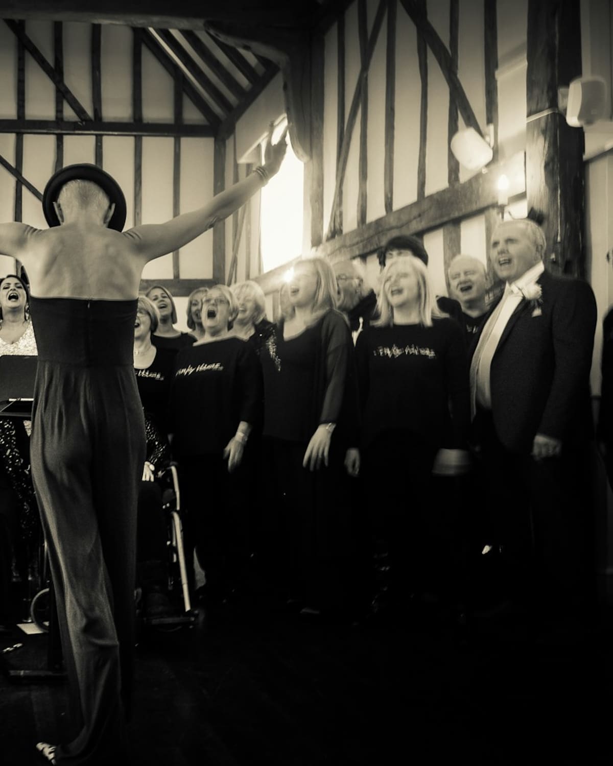 A choir leader with raised arms directing a singing choir