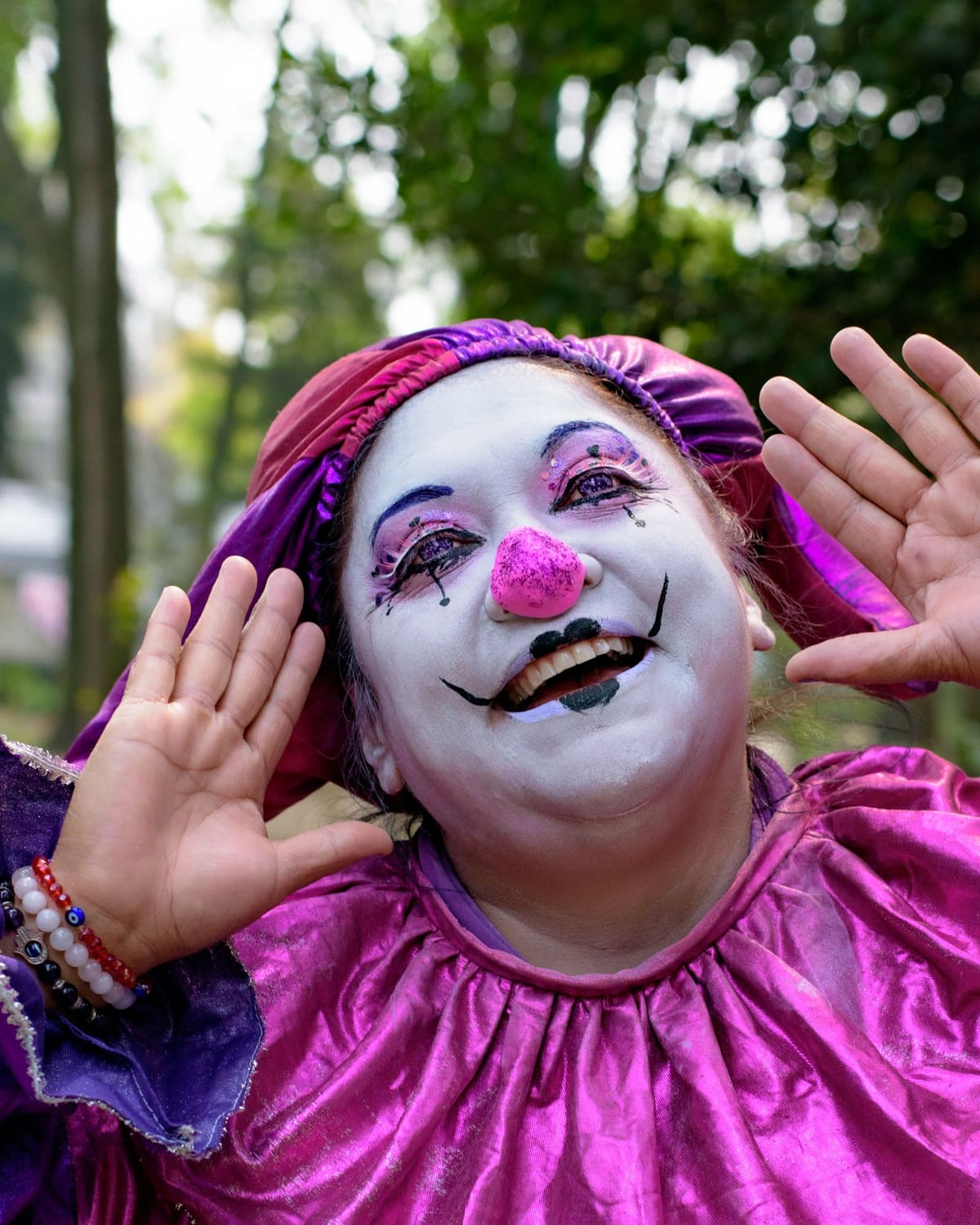 A joyful clown in a bright costume mid-performance outdoors