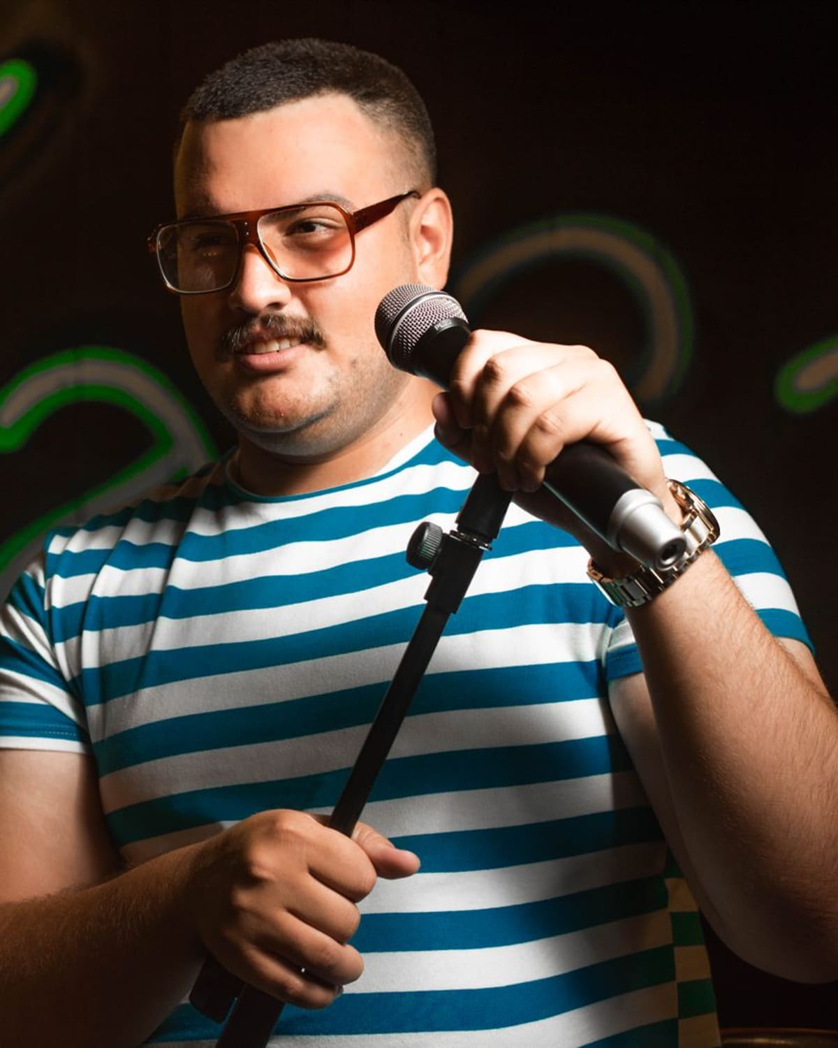 A stand-up comedian at the microphone under club lights
