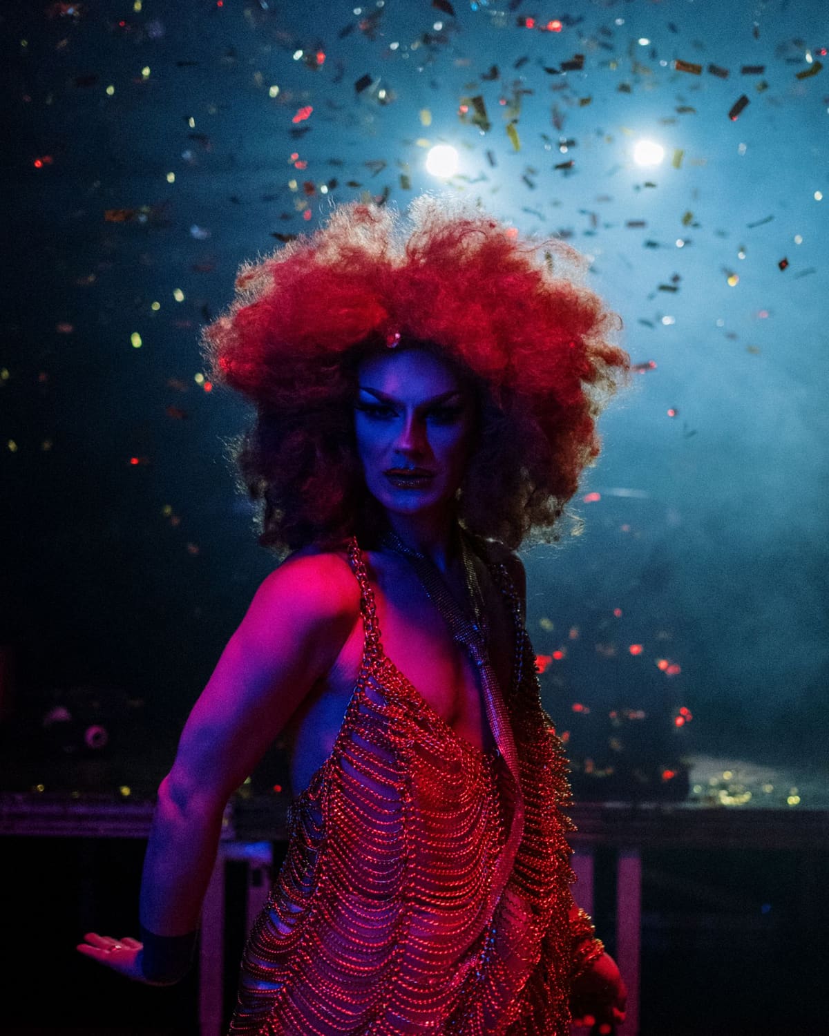 A drag performer in a bold costume commanding the stage under lights