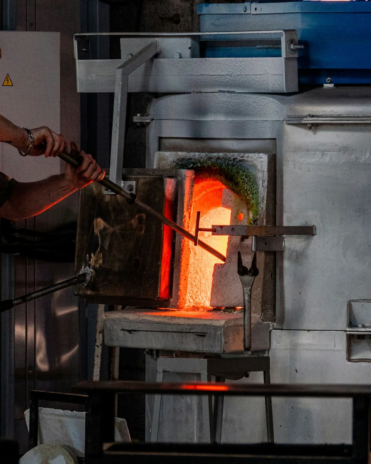 A glassblower's hands turning a pipe in the glowing furnace