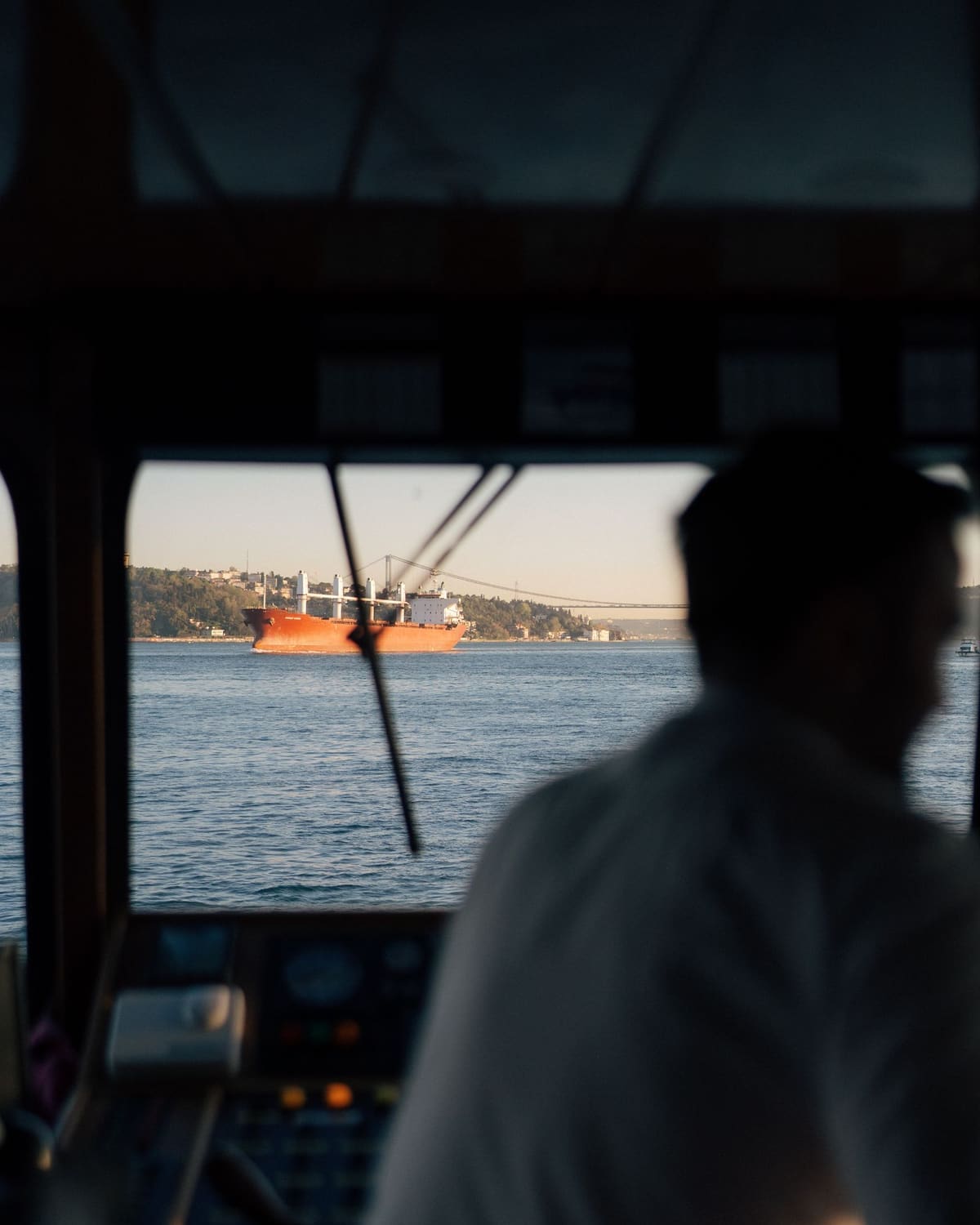 A ship's officer on the bridge watching another vessel cross a busy strait