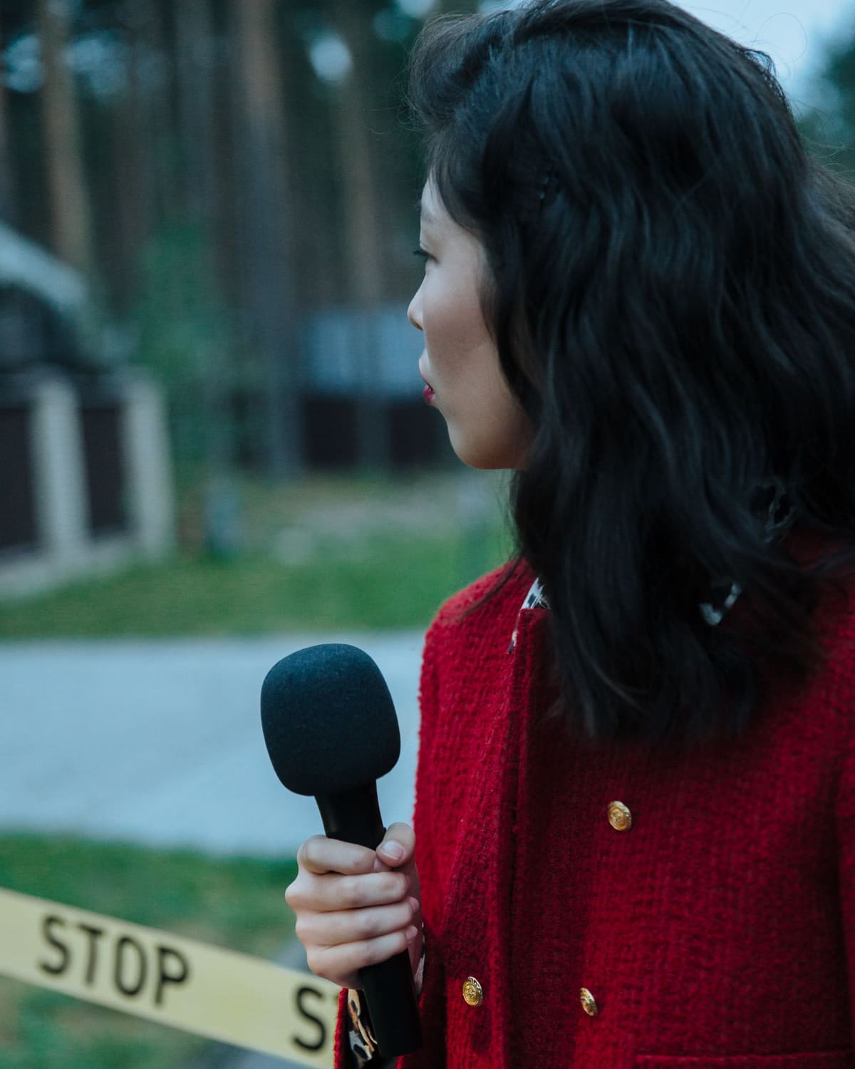 A reporter with a microphone reporting from behind police tape
