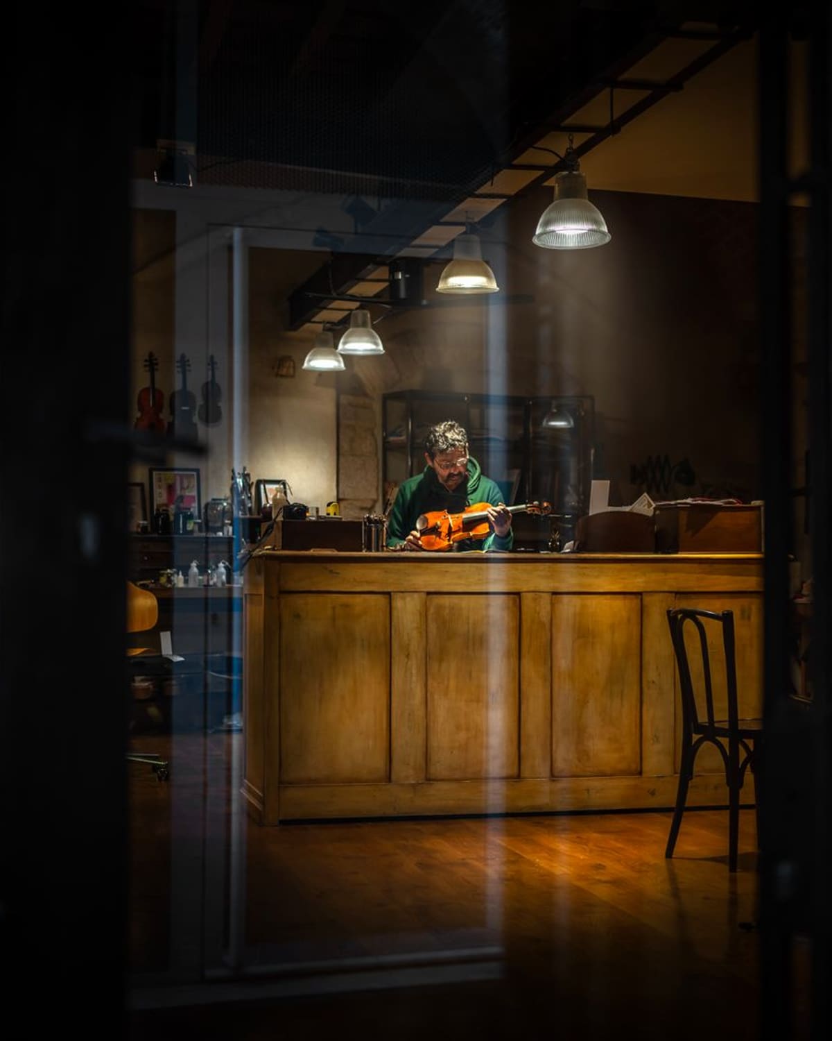 A luthier at his bench with a violin, in a warm-lit workshop