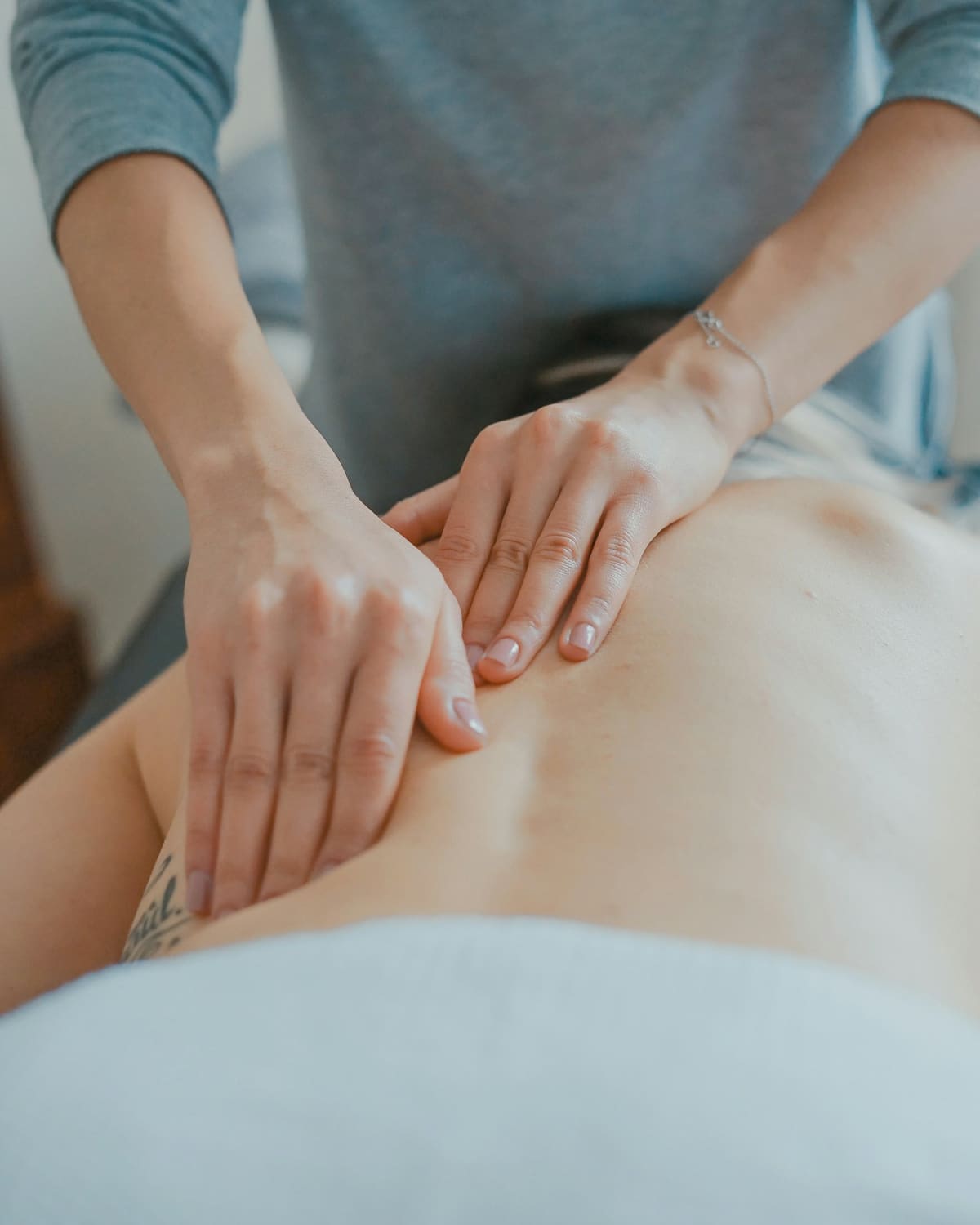 A massage therapist's hands working across a person's back