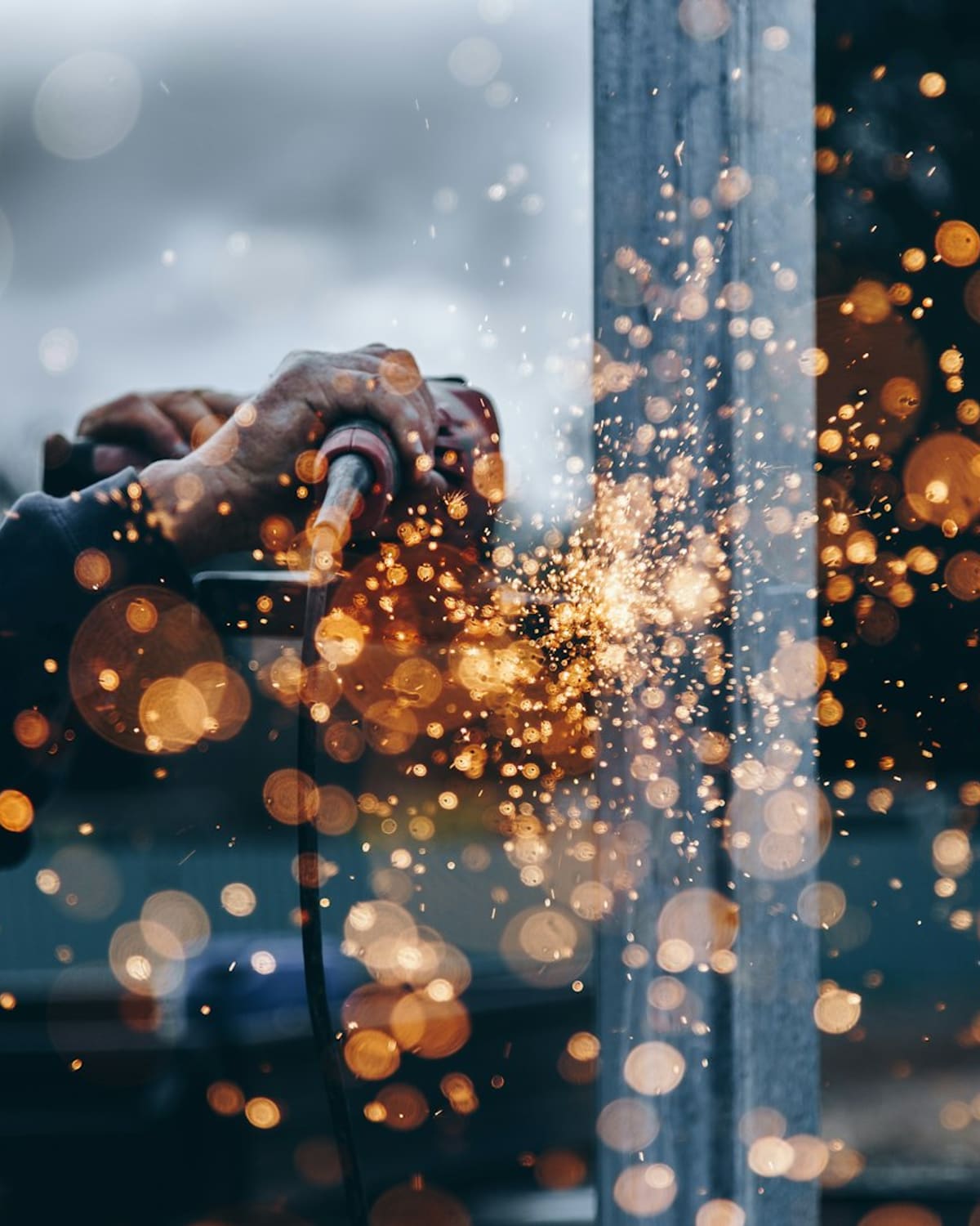 A metalworker's hands guiding a grinder, sparks flying