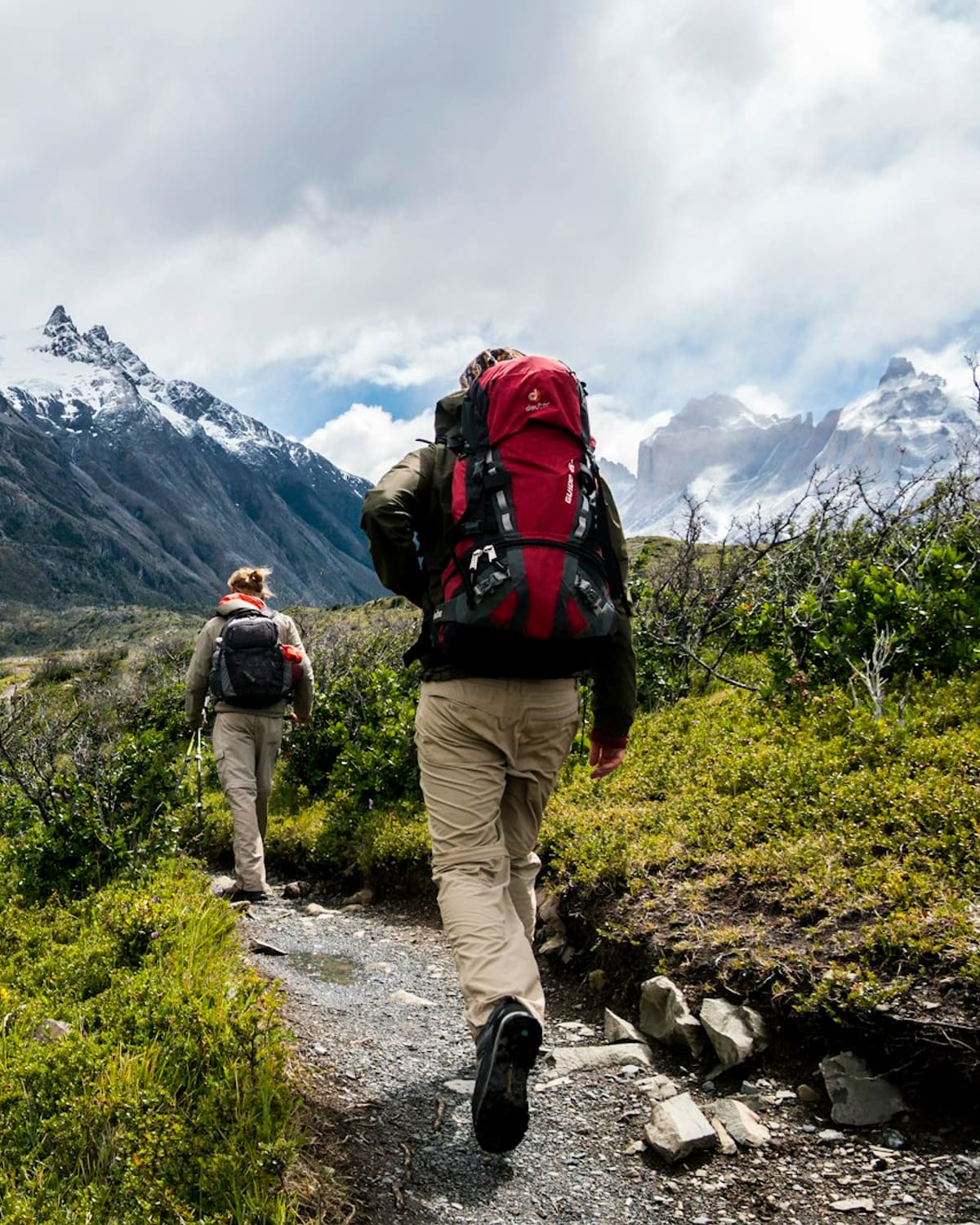 A guide leading a hiker up a mountain trail