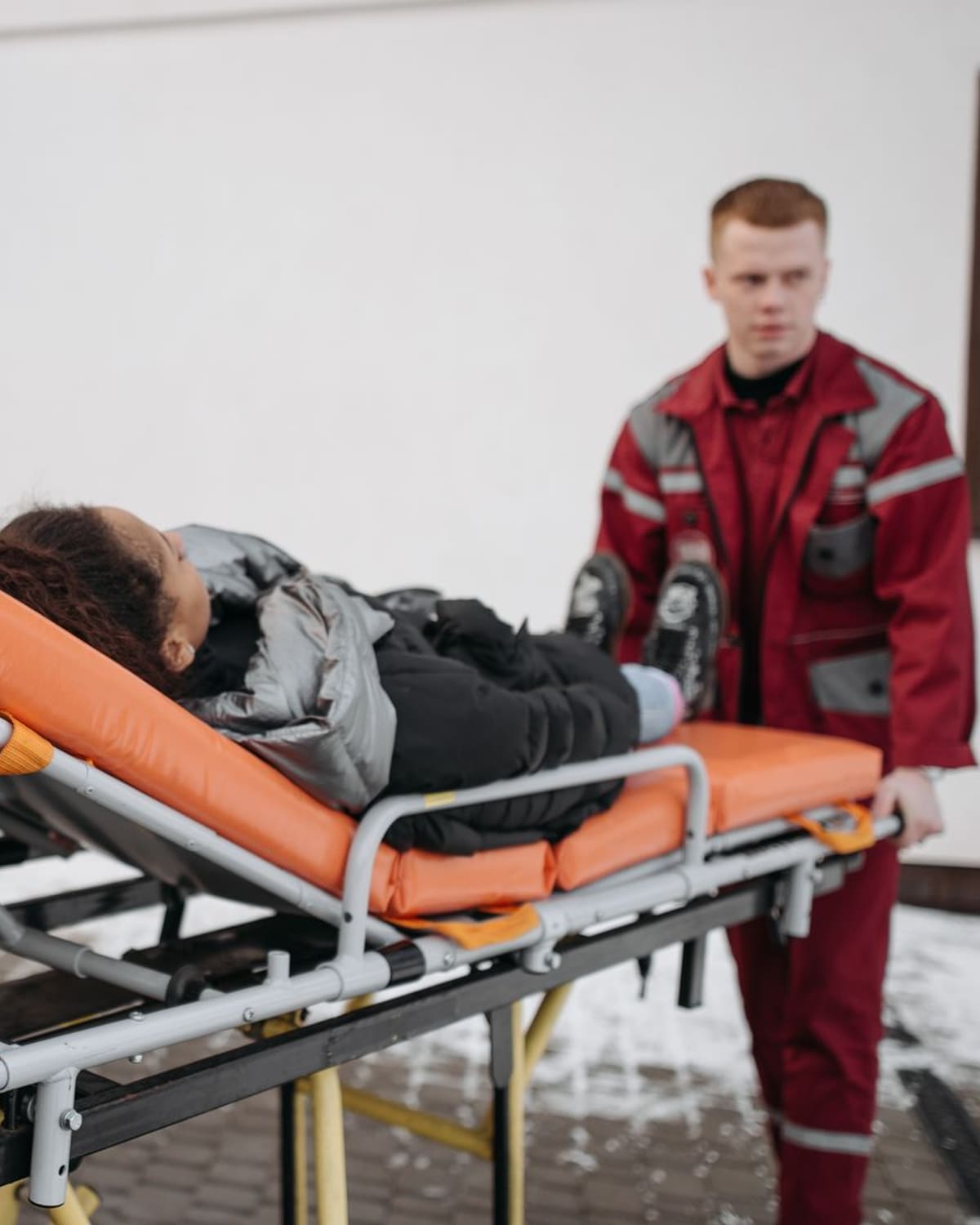 A paramedic moving a patient on a stretcher to the ambulance
