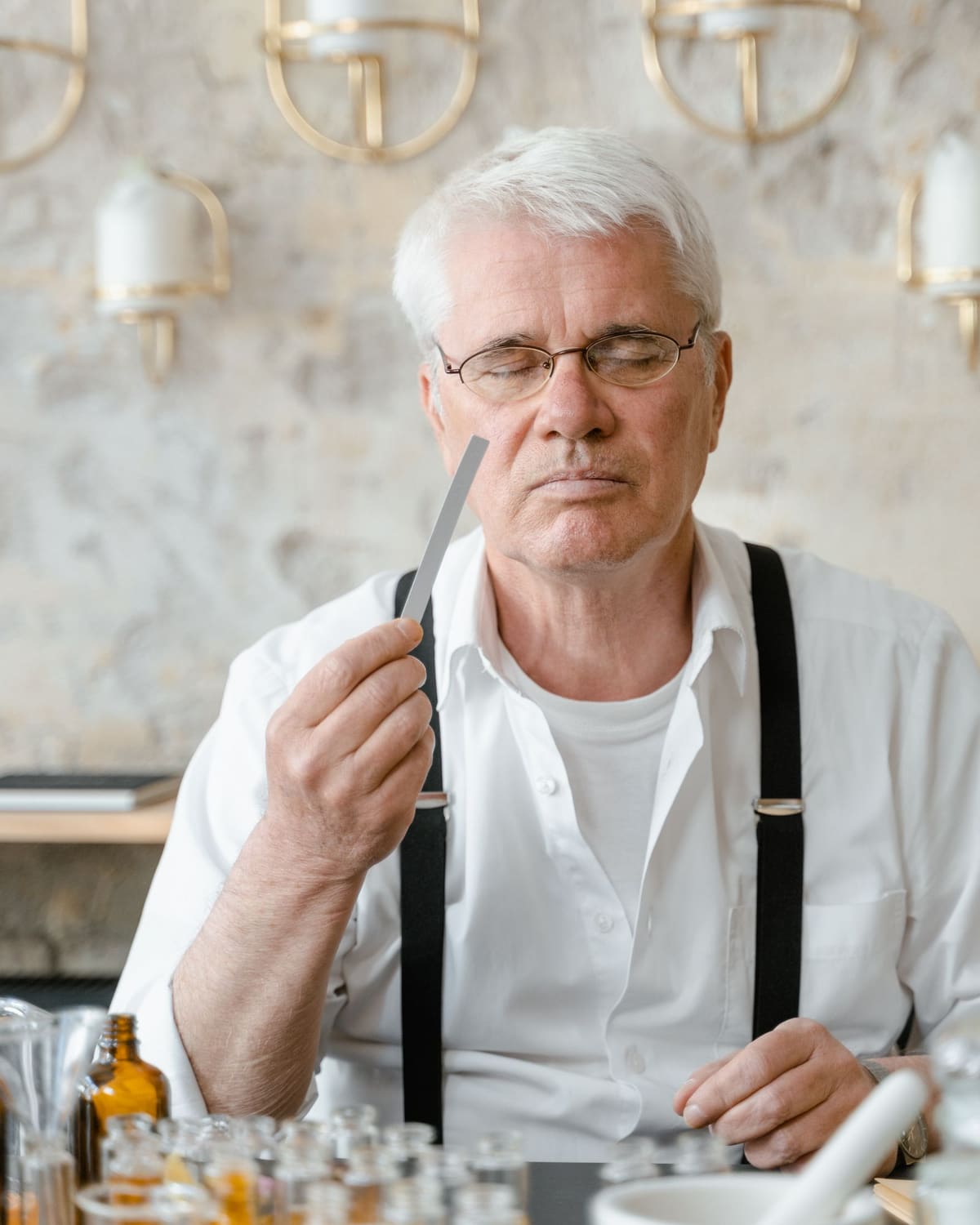 A perfumer with eyes closed smelling a fragrance strip at the bench