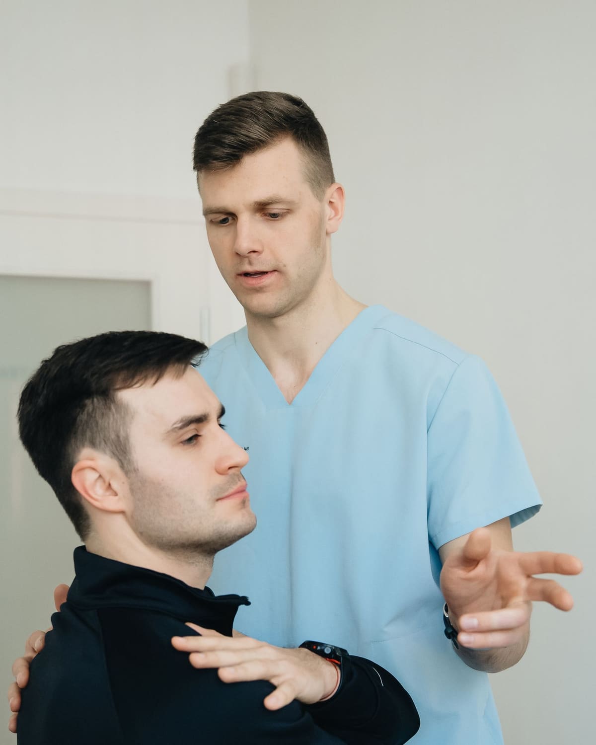 A physical therapist guiding a patient's shoulder in a clinic