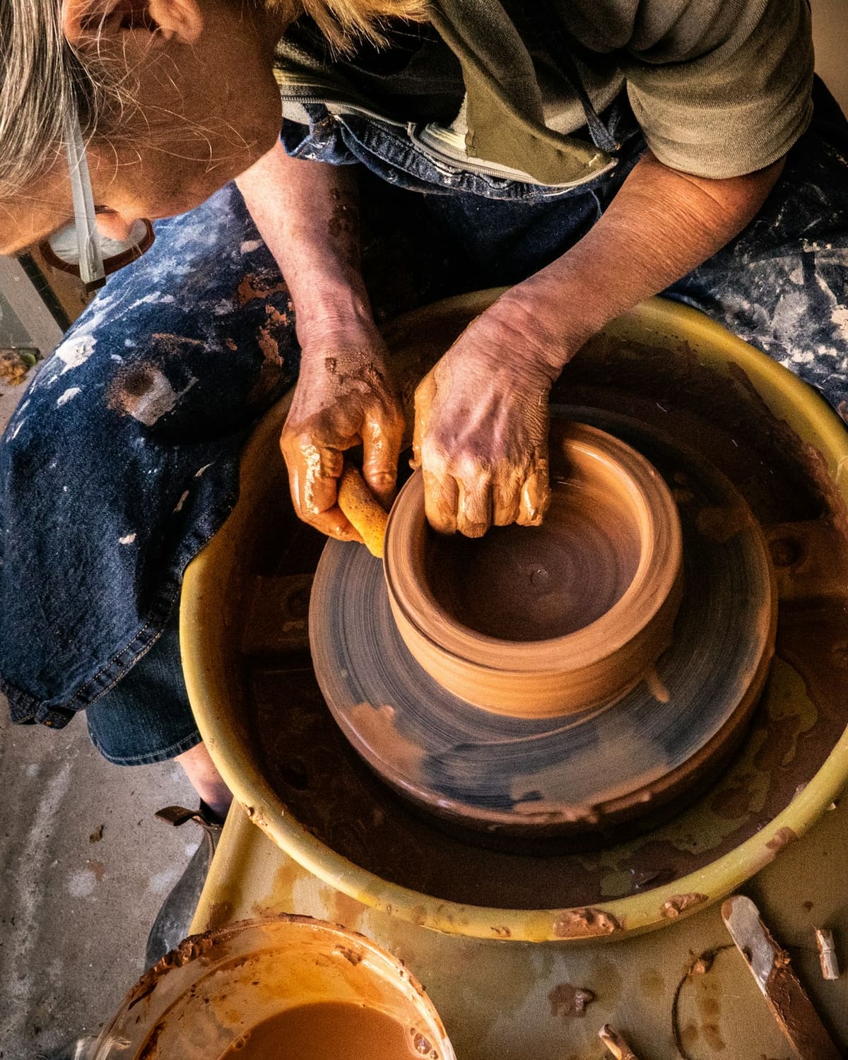 Hands shaping wet clay on a wheel