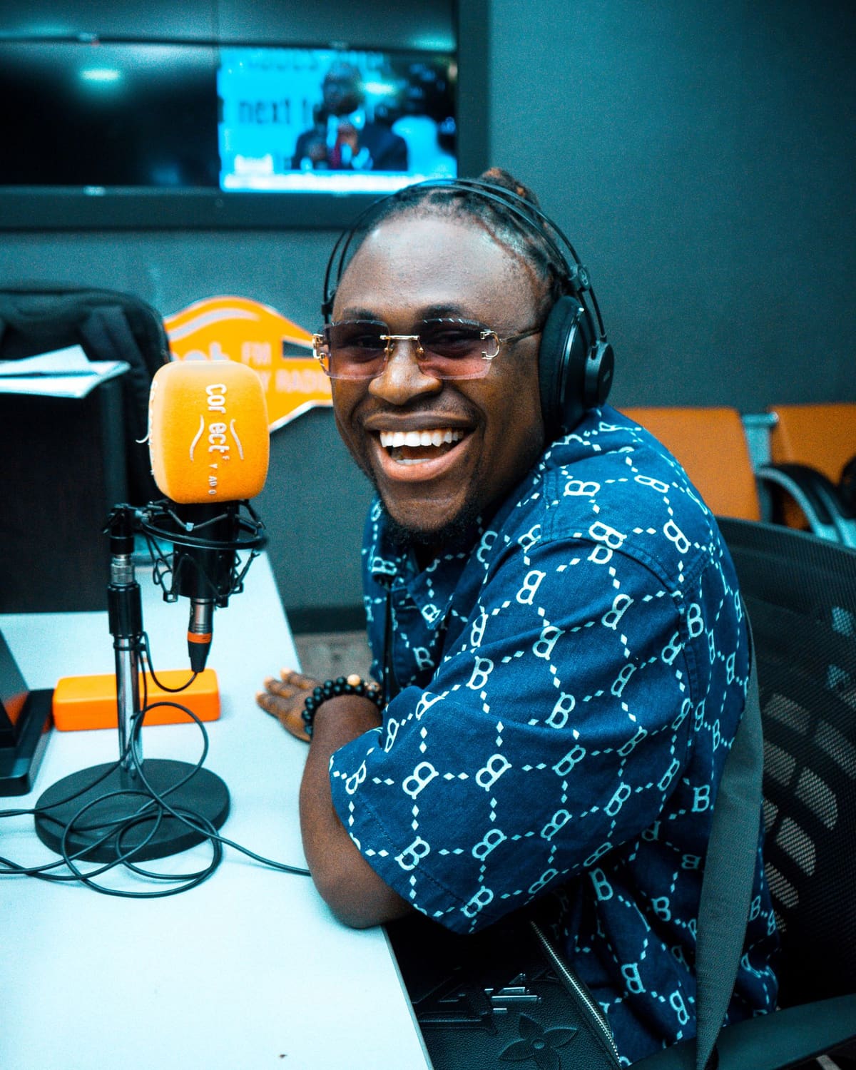 A smiling radio host laughing at the microphone in a studio