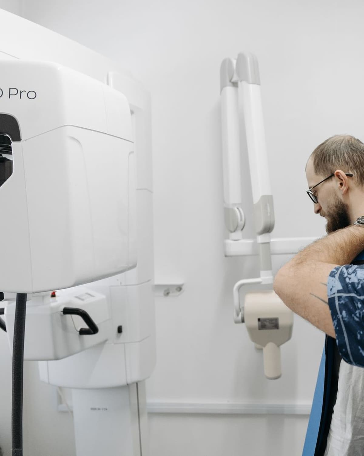 A radiographer gently positions a patient against the X-ray machine before an exam.