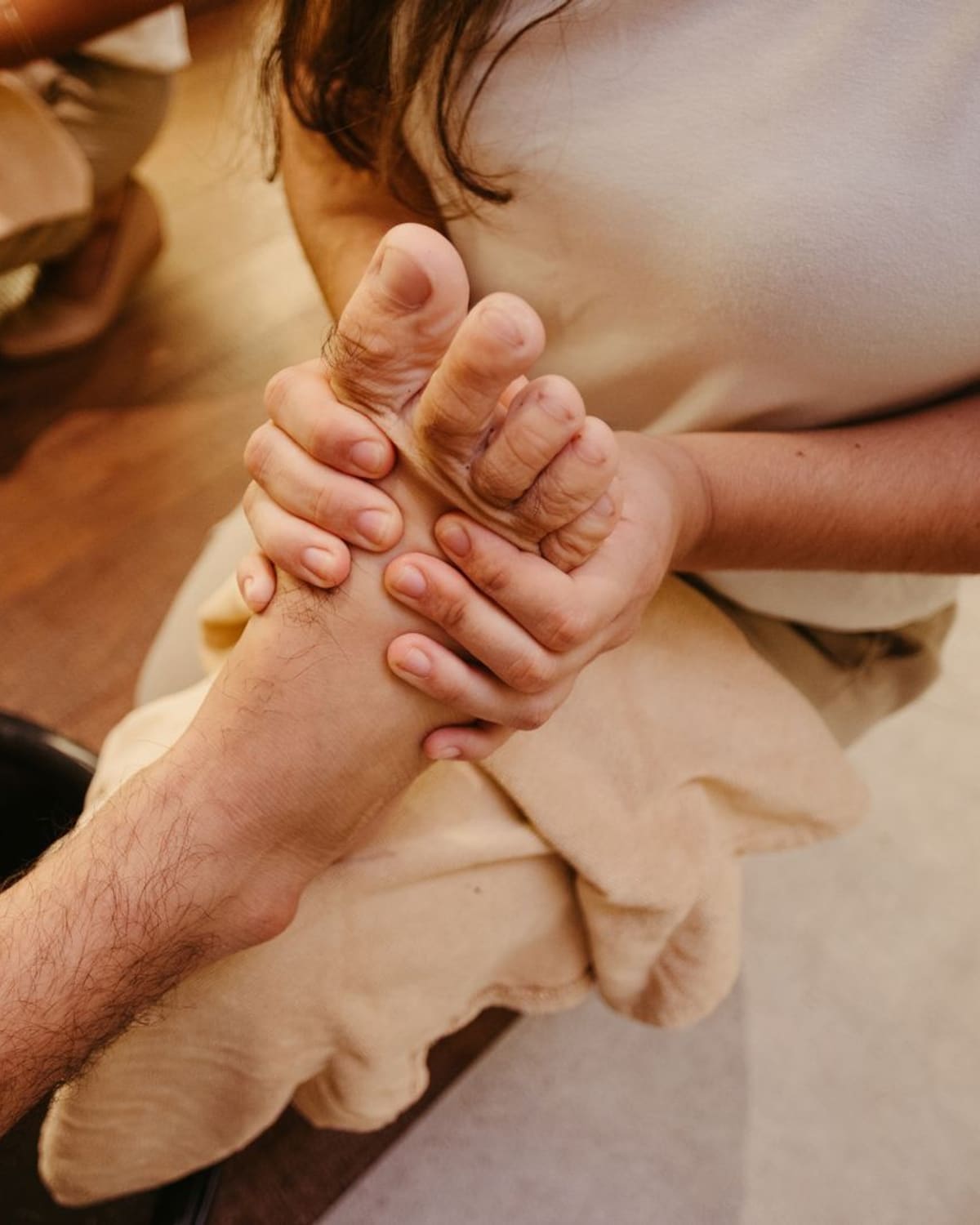 Reflexologist pressing firmly on the sole of a client's foot during a treatment.