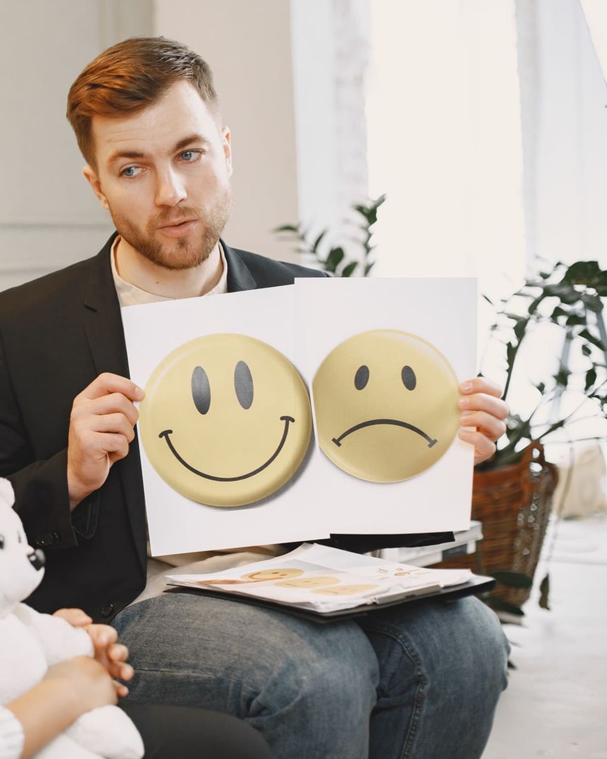 A speech therapist and a child face each other, using expression cards to practise together.