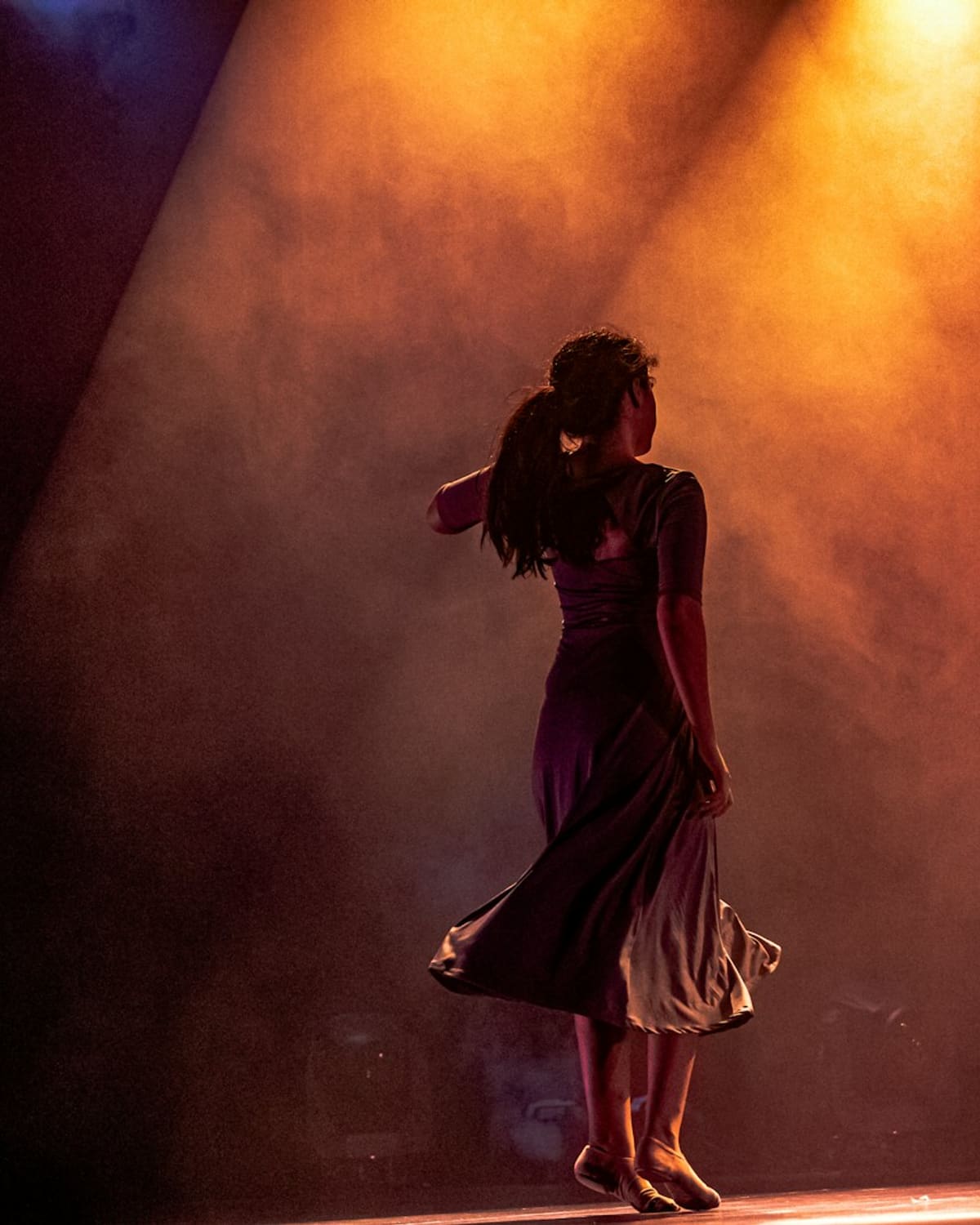 A performer alone on stage in a warm spotlight