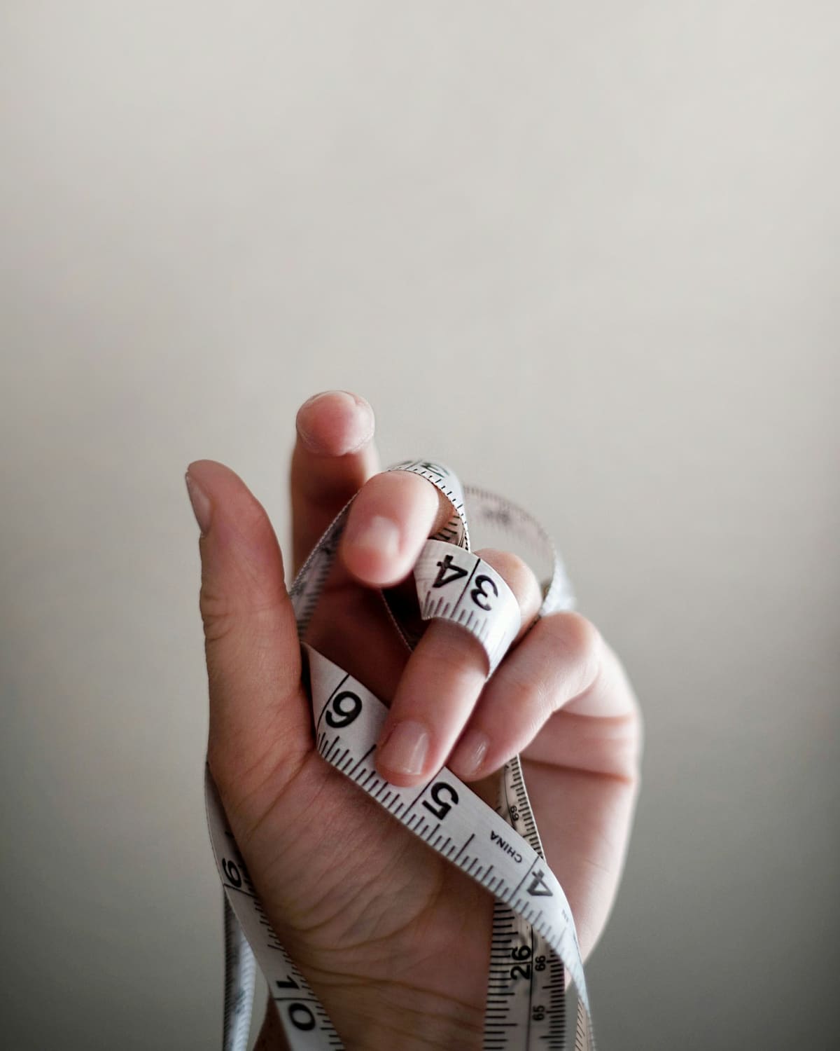 A tailor's hand wound with a measuring tape