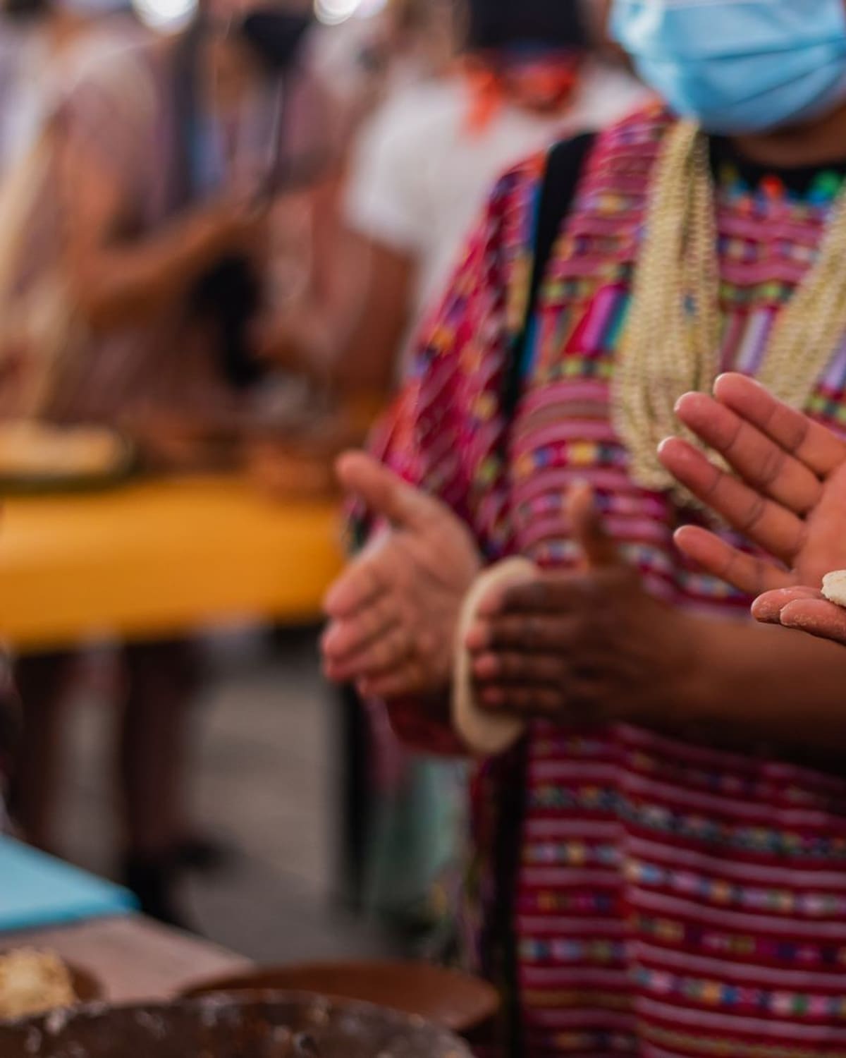 Hands patting fresh masa into tortillas at an outdoor market.