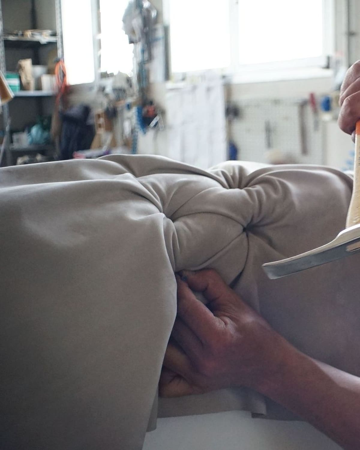 An upholsterer's hands stretching and tacking fabric over a chair
