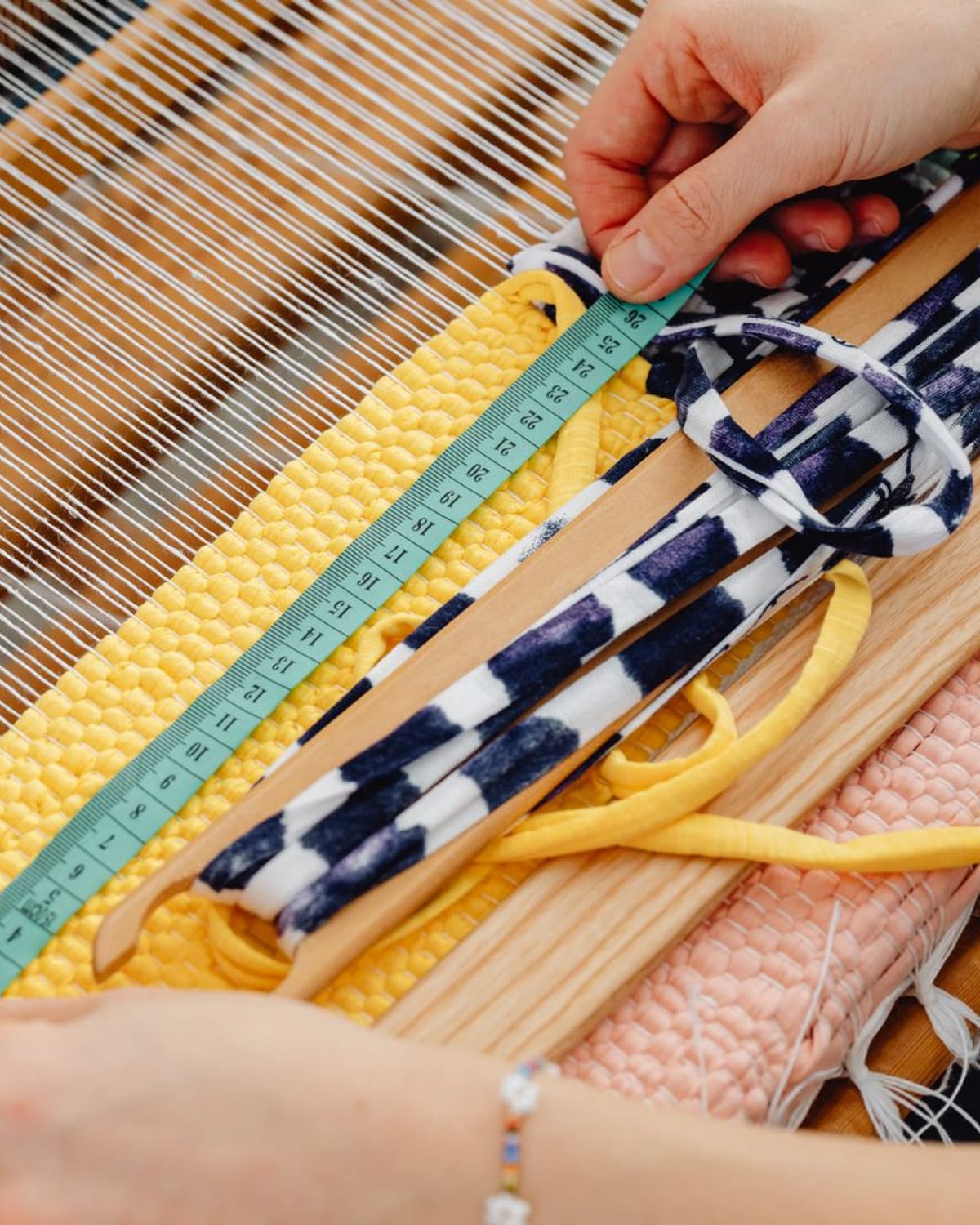 A weaver's hands passing colored thread across a loom